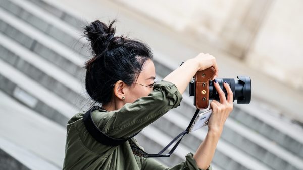 female photographer holding and pointing a DSLR camera