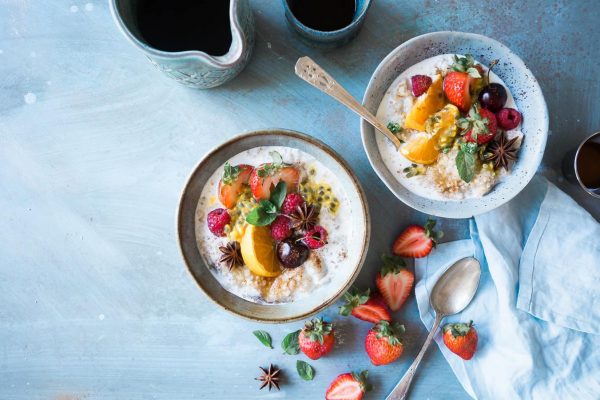 overhead shot of two bowls of oatmeal and fruit with coffee
